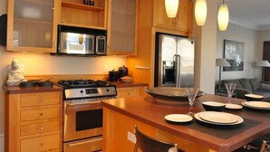 Una cocina moderna con armarios de madera, electrodomésticos de acero inoxidable y una isla central con zona de comedor.