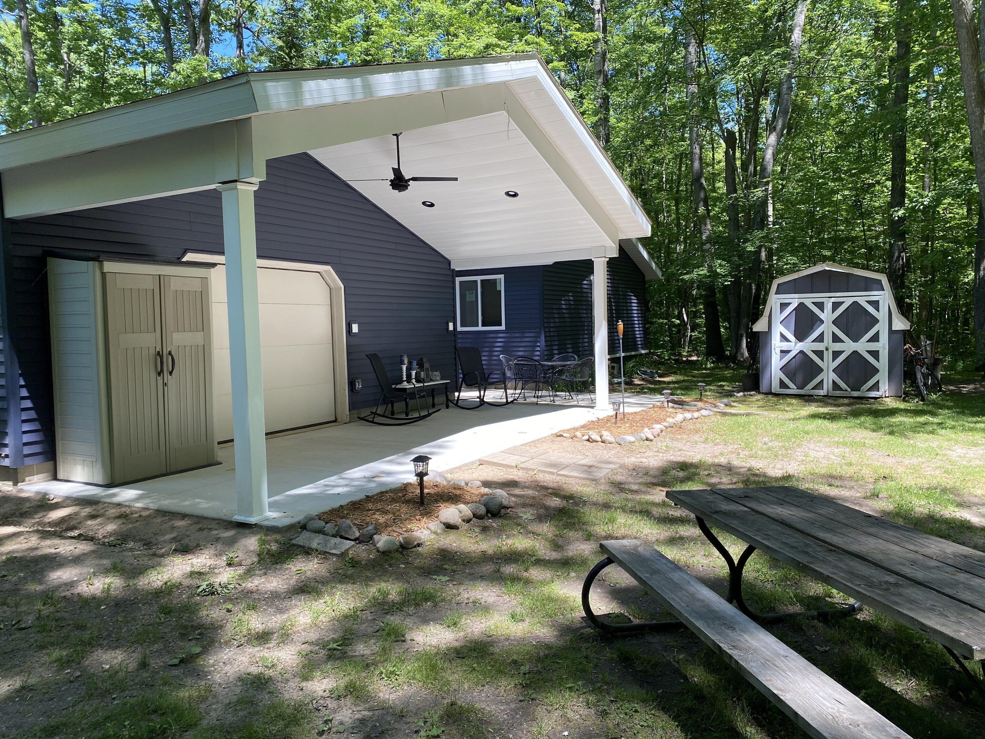 A covered patio with a ceiling fan, a garage, and a small shed.