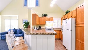 Une cuisine avec des meubles en bois, un réfrigérateur blanc et un plan de travail en granit.