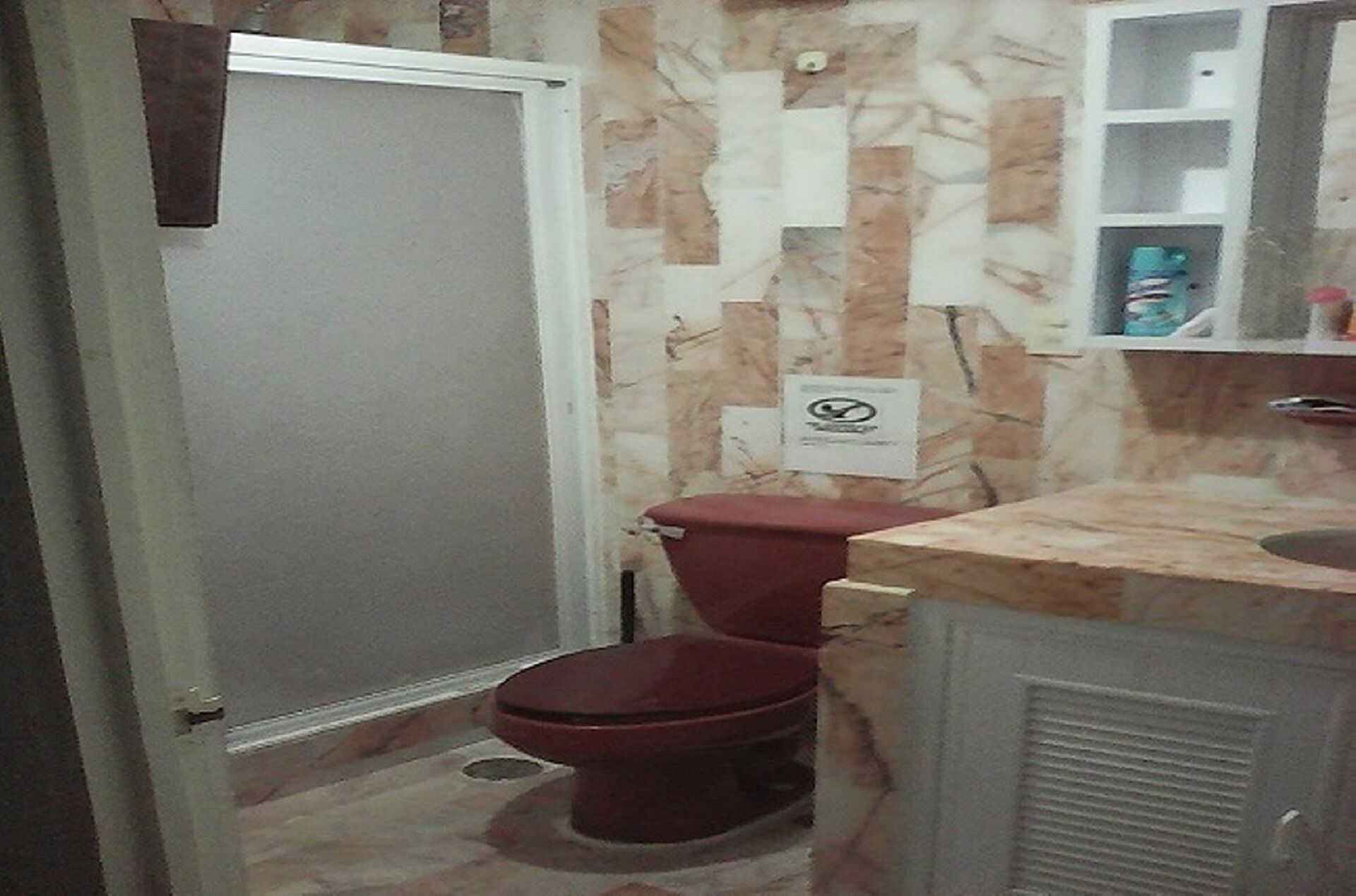 A bathroom with a toilet, a sink, and a cabinet.