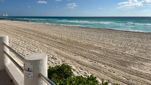 A beach with a railing and a sign indicating a no swimming area. -    Quality Cancun Condo Rental Within Your Vacation Budget?                      (Cancún)