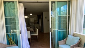 A room with a sliding glass door leading to a dining area, wicker furniture, and a tiled floor. - Spacious Garden Retreat at Vistamar Combate, WiFi, full A/C, walk to the beach (Cabo Rojo)