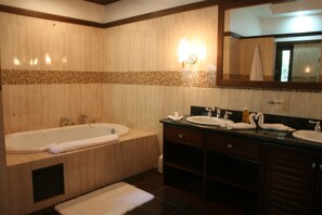 Bathroom features a bathtub, two sinks, and a vanity with a mirror.