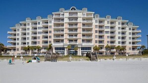 Een hotel met meerdere verdiepingen, balkons, uitzicht op zee en een bord dat een ligging aan het strand aangeeft.