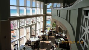 Een restaurant met grote ramen met uitzicht op een strand.