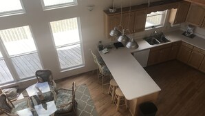 A modern kitchen with a large island, wooden cabinets, and a dining area with wicker chairs. - Gulf Front House, BoatDock/Spectacular View, Central A/C (Horseshoe Beach)