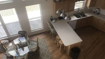 Une cuisine moderne dotée d’un grand îlot central, de meubles en bois et d’un coin repas avec des chaises en osier.