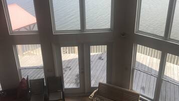Une pièce spacieuse avec de grandes fenêtres donnant sur une terrasse en bois et une plage.