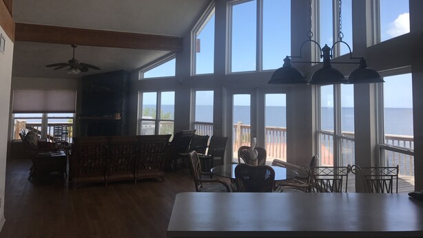 A spacious room with large windows, wooden beams, and a ceiling fan. - Gulf Front House, BoatDock/Spectacular View, Central A/C (Horseshoe Beach)