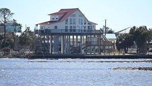A waterfront house with a balcony, a red roof, and a view of the water. - Gulf Front House, BoatDock/Spectacular View, Central A/C (Horseshoe Beach)
