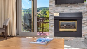 Una camera con camino, una porta scorrevole in vetro che dà su un balcone e una TV a schermo piatto montata a parete.