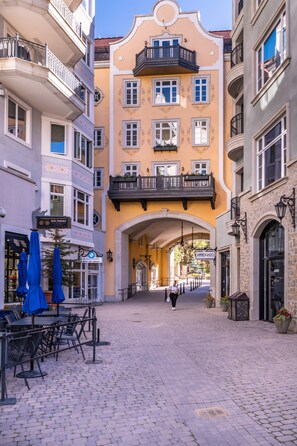 A cobblestone street with outdoor seating, a yellow building with balconies, and an archway. - 1 min. walk to slopes!Mountain view! Steps to ski lift/gondola, shops & dining! (Vail)