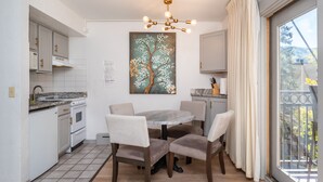 Una cucina moderna con mobili bianchi, un piano di lavoro in marmo e un'area pranzo con un tavolo rotondo e quattro sedie.