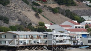 A coastal residential area with multi-story houses on stilts, featuring balconies and a view of the beach.