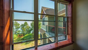A window with a view of a house and a swing set in the yard.