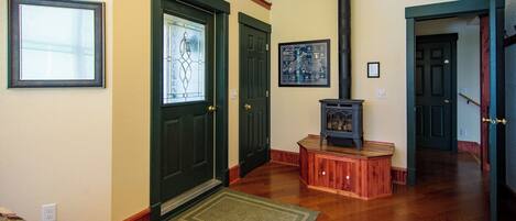 A room with wooden flooring, a fireplace, a door with a stained glass window, and a framed map on the wall.