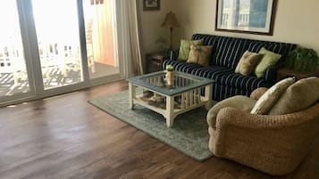 A living room with a striped sofa, a glass coffee table, and a wicker chair.