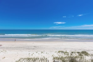 Una playa con cielo despejado, orilla arenosa y algunas personas.