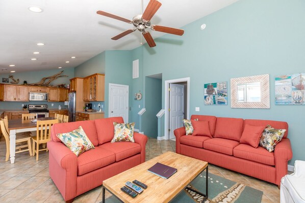 A living room with two red sofas, a wooden coffee table, and a ceiling fan.