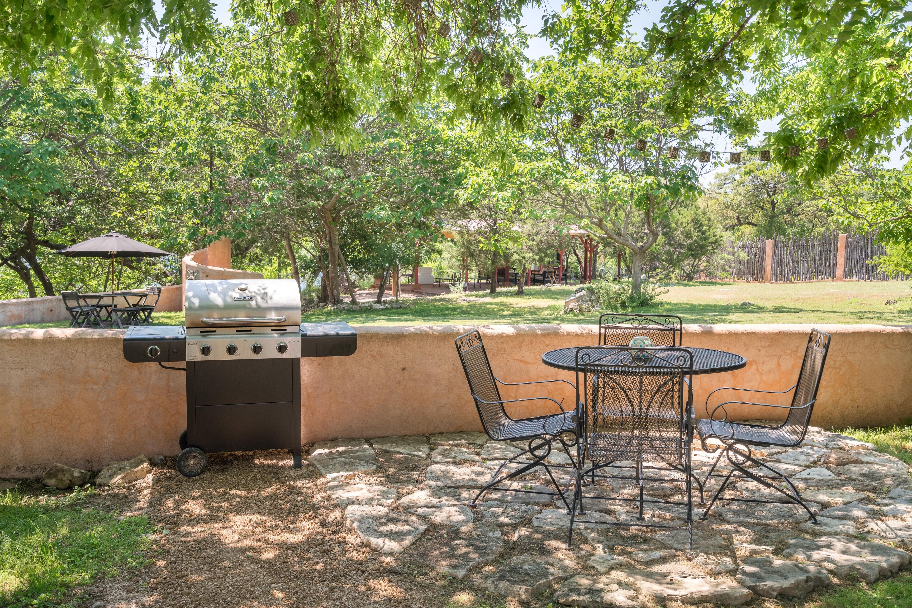 Un patio exterior con una parrilla, una mesa y sillas.