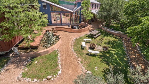 Une maison moderne dotée d’une allée incurvée, d’un patio aménagé avec des sièges et d’un jardin bien entretenu.