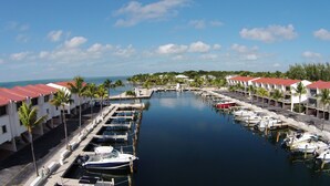 A marina with docked boats, a clear sky, and buildings with red roofs. - Waterfront Islamorada Condo – Heated Pool, Marina & Deeded Boat Slip (Tavernier)