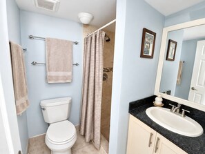 A bathroom with a toilet, a shower curtain, a sink, and a mirror. - Futura Yacht Club Islamorada Condo – Heated Pool, Marina & Deeded Slip (Tavernier)