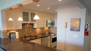 A modern kitchen with a central island, stainless steel appliances, and pendant lighting. - Waterfront Islamorada Condo – Heated Pool, Marina & Deeded Boat Slip (Tavernier)