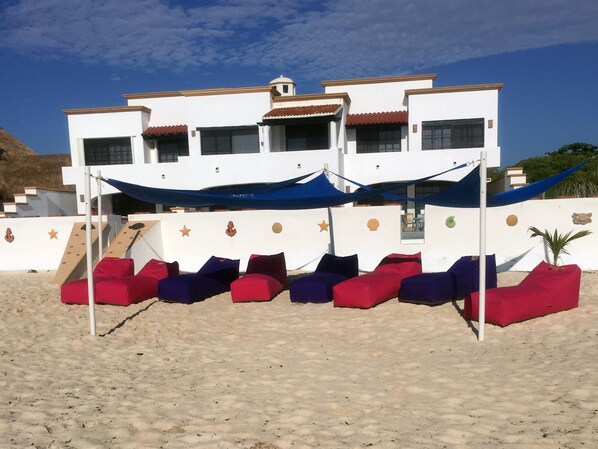 A beachside building with multiple balconies, a staircase, and colorful outdoor seating. - Secret Beach Shell Villa - on Beach - Private Pool - Owner is a Chef - Very Safe (Playa del Carmen)