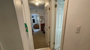 A narrow hallway with beige tiled flooring leading to a room with a door. - Okemo Mt. Family Affordable 1st floor, village shuttle, walk to town, Dogs OK  (Ludlow)