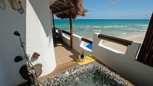 Een balkon met uitzicht op de oceaan, een rieten dak en een betegelde jacuzzi.