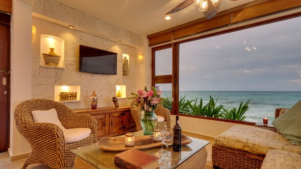Een gezellige woonkamer met rieten meubels, een flatscreen televisie en uitzicht op de oceaan.