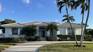 A single-story house with a tiled roof, a front entrance, and a paved driveway. - Sunny Pool & Spa inside Lanai! Dock and Water access! 3bd 2bath home. (Marco Island)