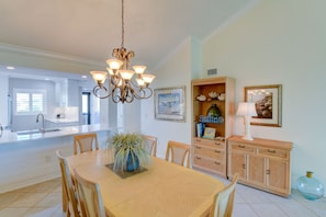 A modern kitchen with white cabinets, a central island, and a chandelier.
