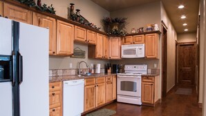A kitchen with wooden cabinets, a white refrigerator, a microwave, and an oven.
