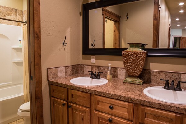 A bathroom with two sinks, wooden cabinets, a large mirror, and a shower area.