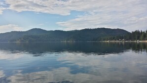 A calm lake with a forested mountain in the background.