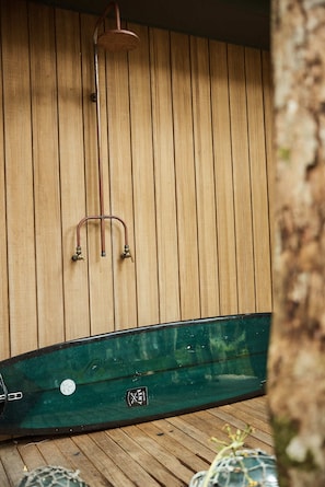 Un sauna en bois avec un sol vert, une pomme de douche en métal et un logo bien visible sur le sol.