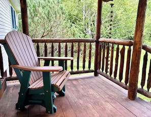 Terraza de madera con sillas Adirondack y barandilla de madera.