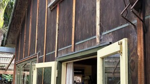 Une maison en bois avec une grande porte ouverte donnant sur une pièce où se trouve un réfrigérateur blanc.