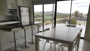 Une cuisine moderne avec un coin repas, de grandes fenêtres et une vue sur le quartier.