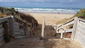 Un escalier en bois menant à une plage d’où l’on a une vue sur l’océan.
