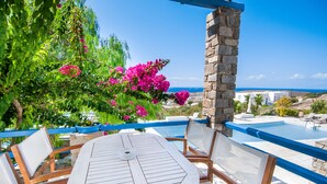 A round table with chairs, a stone pillar, and a view of a swimming pool and the sea. - Sea view house with swimming pool ISLA summer homes (Paros)