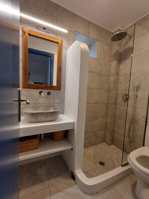 A modern bathroom with a stone sink, a wooden-framed mirror, a shower enclosure, and a toilet. - Sea view house with swimming pool ISLA summer homes (Paros)