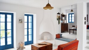A spacious living room with a large wooden chest, a vibrant striped armchair, and a fireplace. - Sea view house with swimming pool ISLA summer homes (Paros)