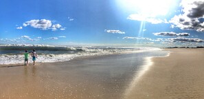 Na praia, espreguiçadeiras, guarda-sóis, toalhas de praia 