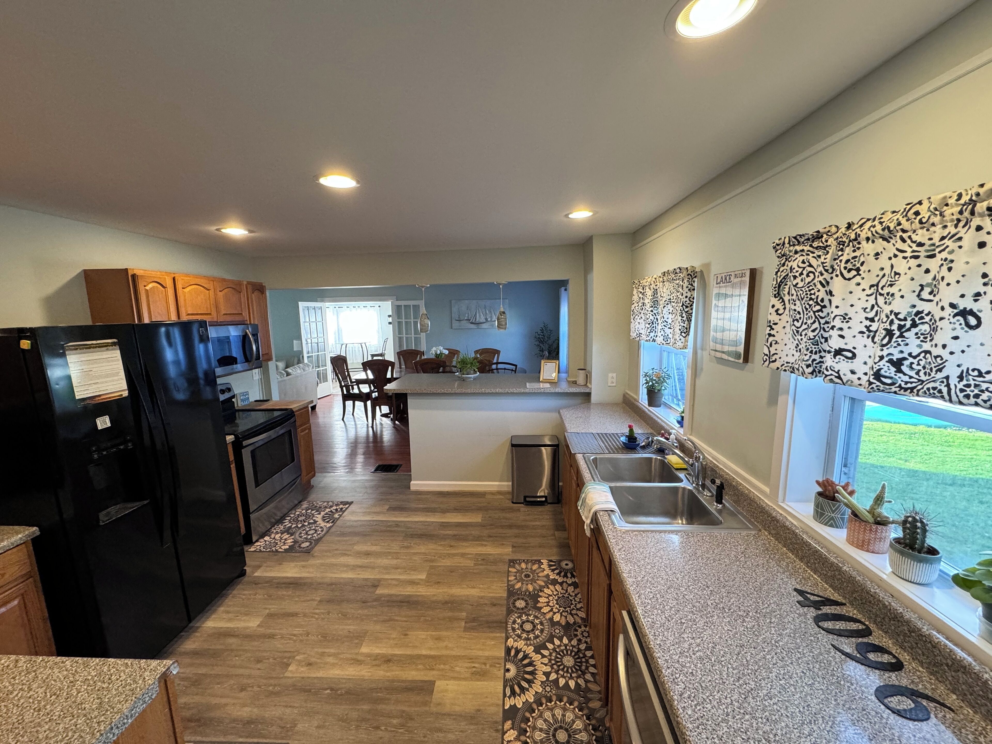 A modern kitchen with granite countertops, a black refrigerator, and a dining area with wooden chairs.