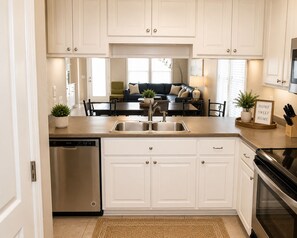 A kitchen with white cabinets, a stainless steel dishwasher, and a black oven.