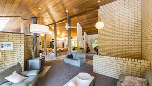 A modern interior with brick walls, a wooden ceiling, and a dining area with chairs and a table. - Fern Ridge Private Resort/ Wedding / Function Venue (Coffs Harbour)