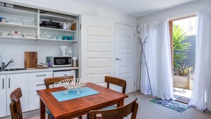 A compact kitchen with white cabinets, a microwave, and a dining table with chairs.